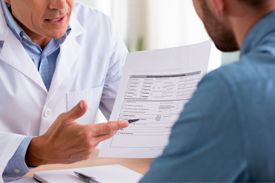Врач указывает ручкой на медицинский документ